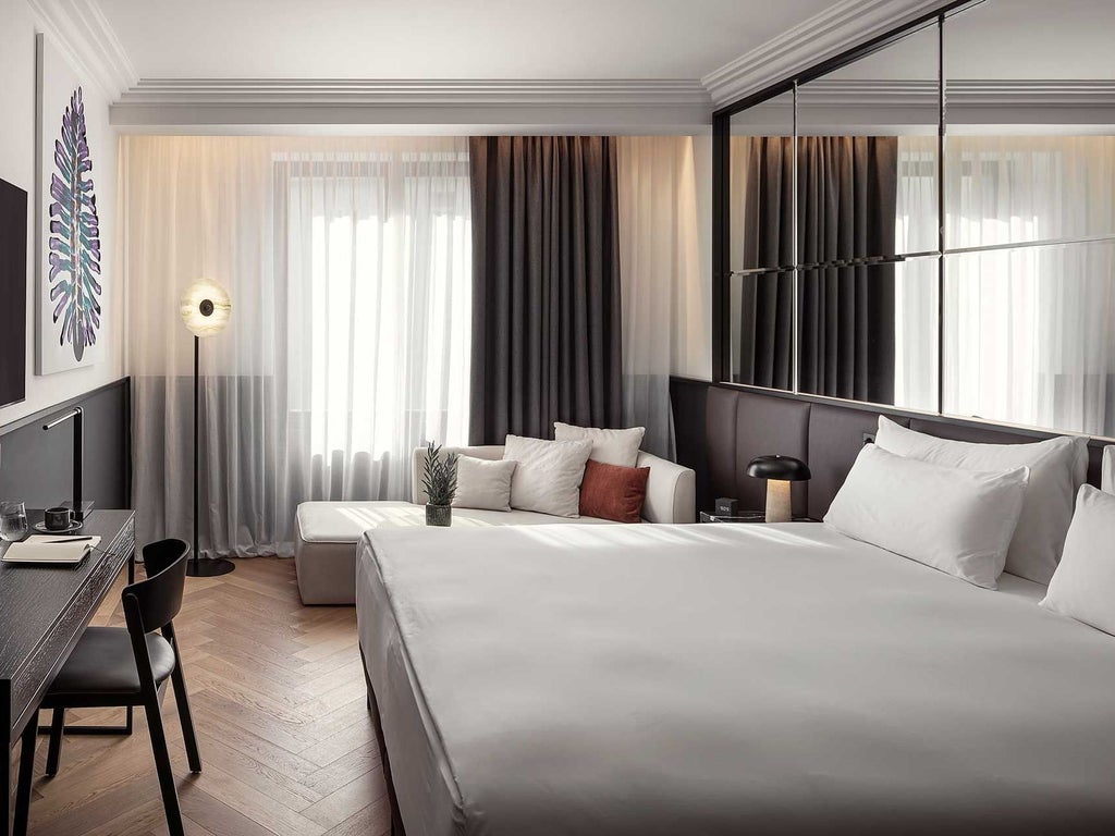 Elegant deluxe hotel room with modern Czech design, plush white bedding, sleek dark wood furniture, and soft ambient lighting in Prague