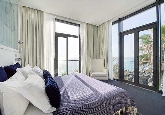 Elegant junior suite with ocean-facing balcony, featuring contemporary Portuguese design, soft neutral tones, and panoramic coastal views of Cascais shoreline