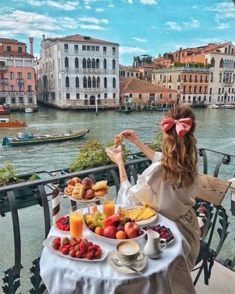 Elegant Venetian palazzo with ornate Renaissance facade, gleaming canal-side windows, and soft evening light reflecting on historic stone walls of luxurious hotel