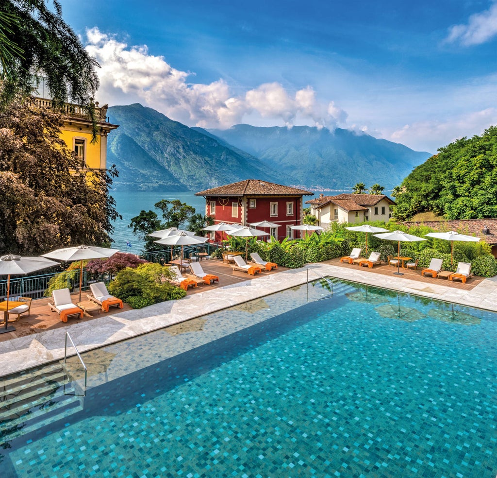 Art Deco-style luxury hotel with ornate facade overlooking Lake Como, featuring manicured gardens and a floating pool on turquoise waters