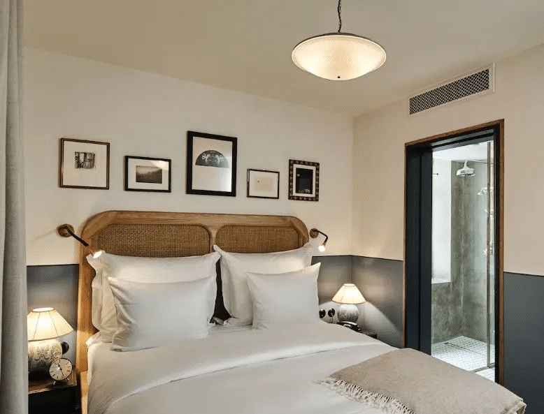 Elegant boutique hotel room with velvet headboard, brass accents, vintage artwork, Danish design furniture and natural light from windows