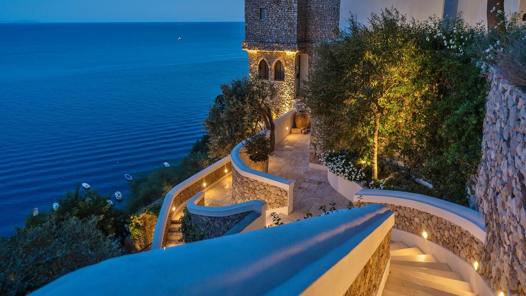 Luxurious cliffside hotel with white terraces and infinity pool overlooking the blue Amalfi Coast waters and Mediterranean landscape