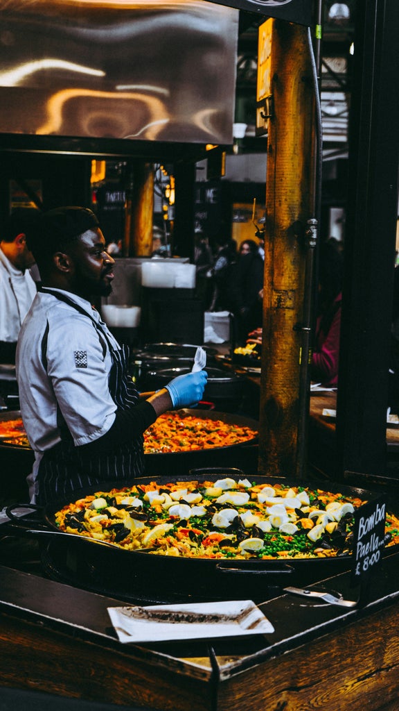 Bustling Borough Market stall with artisan cheese vendor, golden afternoon light, vibrant produce displays, and culinary enthusiasts exploring gourmet food selections