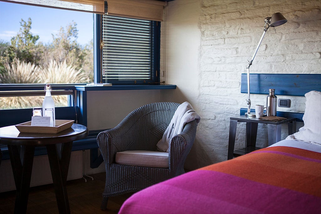 Modern luxury lodge with adobe walls and wooden beams nestled in desert landscape, mountain backdrop and clear blue sky