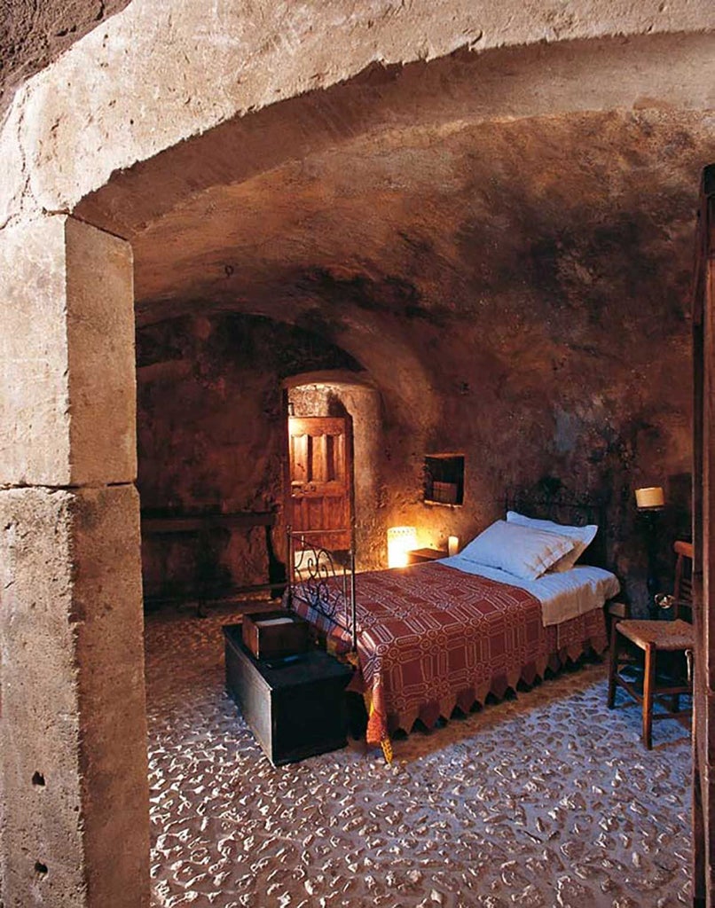 Rustic stone interior of converted stable room at Sextantio Albergo Diffuso, featuring minimalist design with exposed wooden beams and traditional Italian rural elegance