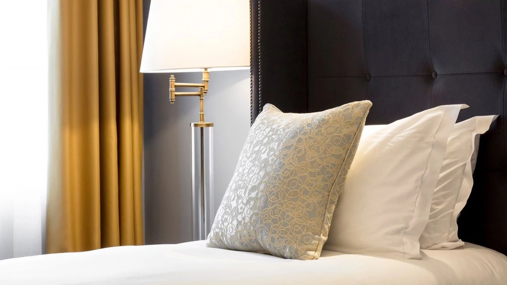 Elegant deluxe hotel room with contemporary Irish design, plush white bedding, modern furnishings, and soft ambient lighting in a sophisticated urban setting.