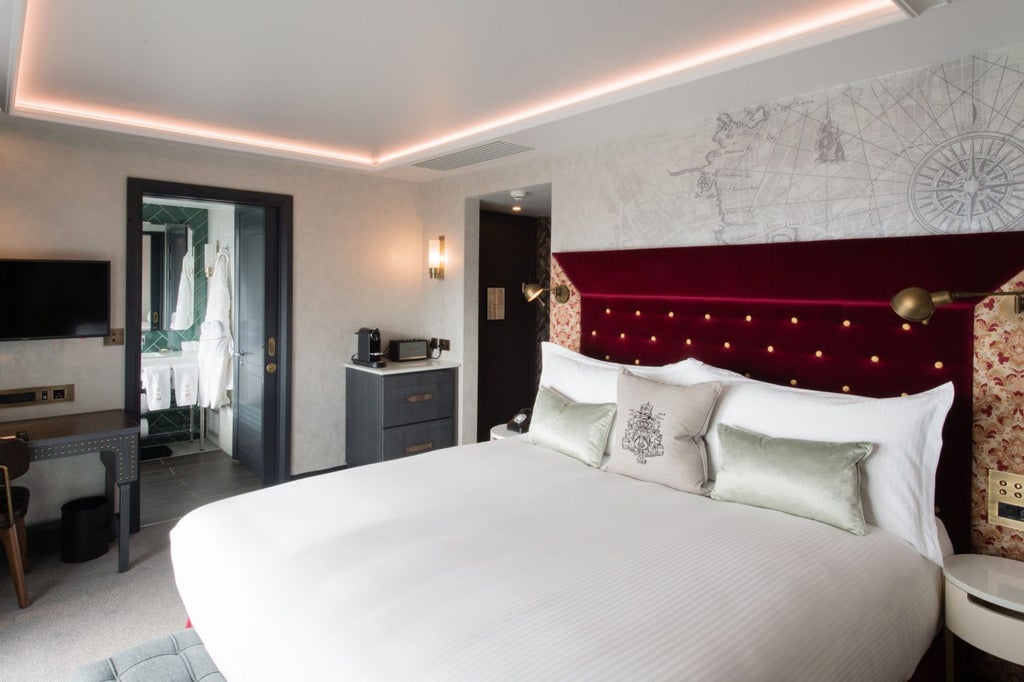 Elegant deluxe studio at Vintry & Mercer hotel with plush king bed, modern wooden furnishings, and warm ambient lighting in a sophisticated UK setting.