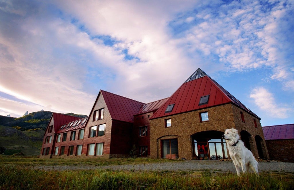 Elegant mountain lodge with wood and stone facade nestled in snow-capped Andes, featuring panoramic windows and upscale terraces