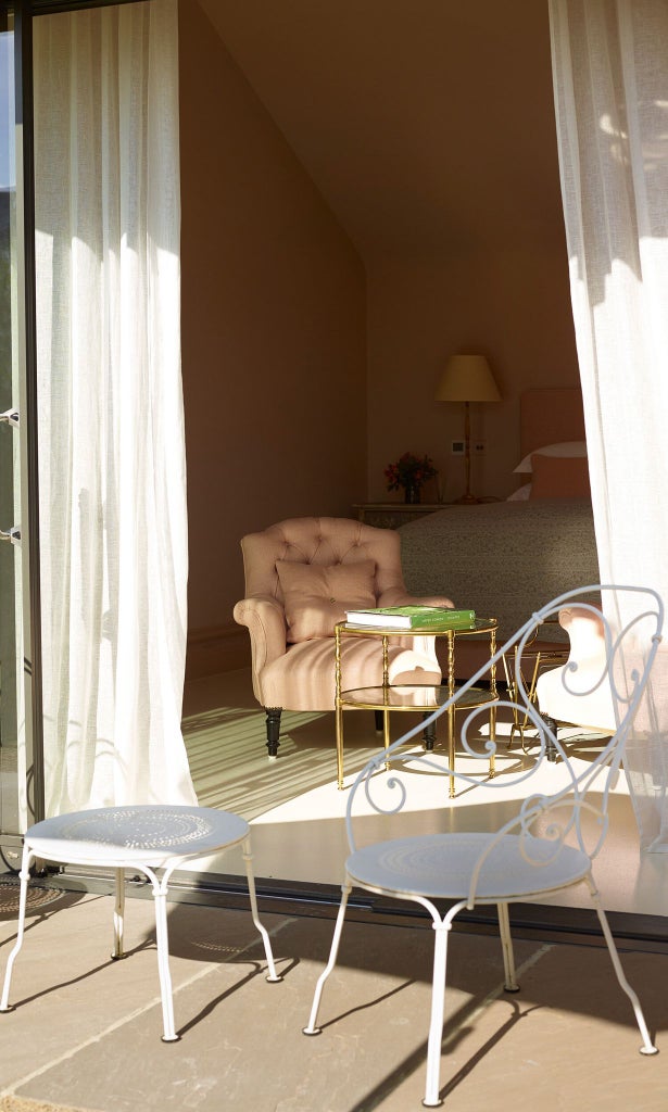 Elegant garden-inspired bedroom with soft green tones, luxurious white linens, and botanical artwork, showcasing refined countryside charm in a UK hotel suite