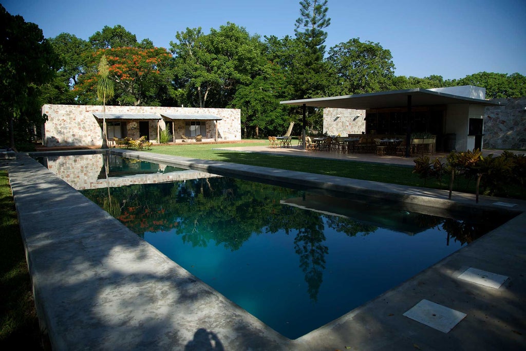 Elegant colonial-style luxury boutique hotel with lush tropical gardens, vibrant stone facade, and traditional Mexican architectural details near scenic landscape