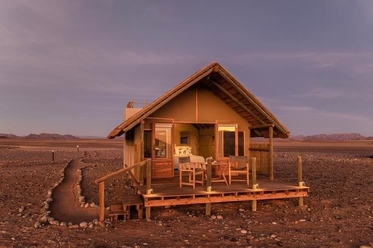 Spacious canvas and thatch room at Kulala Desert Lodge, featuring rustic elegance with warm earth tones and traditional Namibian design elements overlooking desert landscape