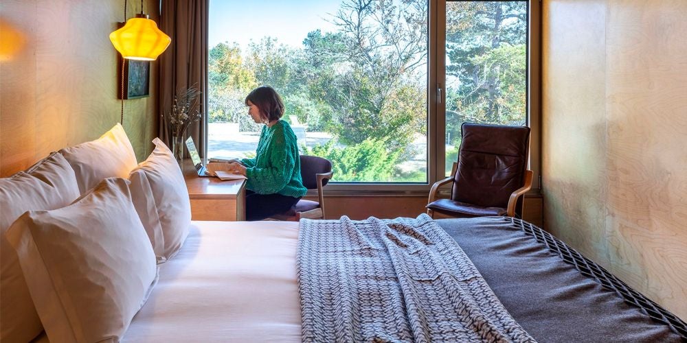 Elegant mountain-view double room at Casa das Penhas Douradas, featuring crisp white linens, minimalist design, and panoramic alpine landscape through large window