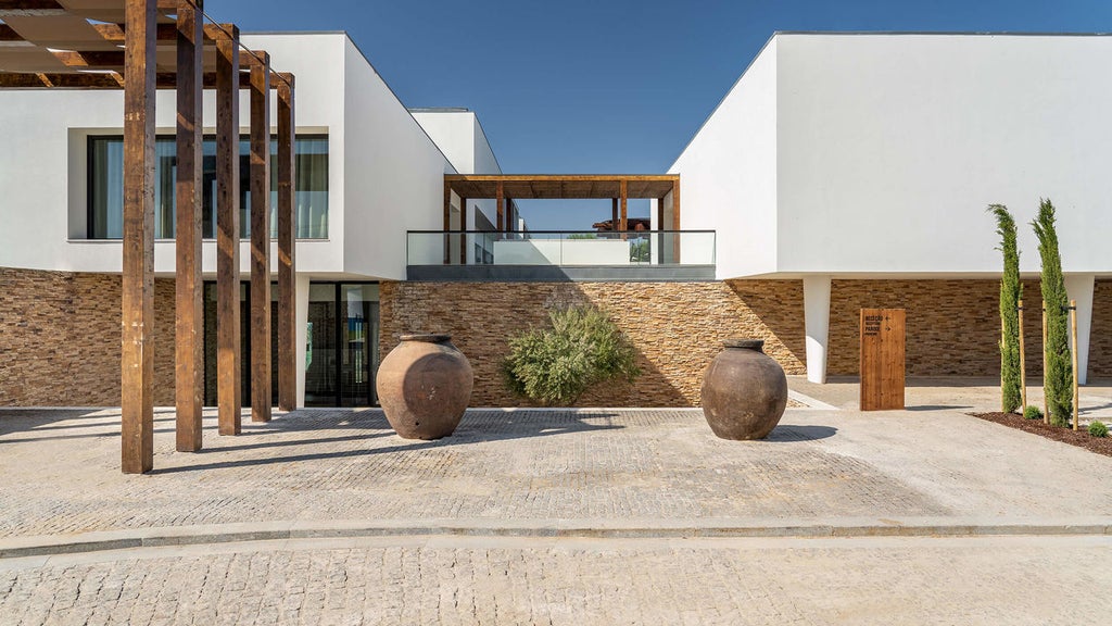 Elegant outdoor infinity pool surrounded by modern loungers and umbrella cabanas at Octant Evora hotel, overlooking Portuguese countryside