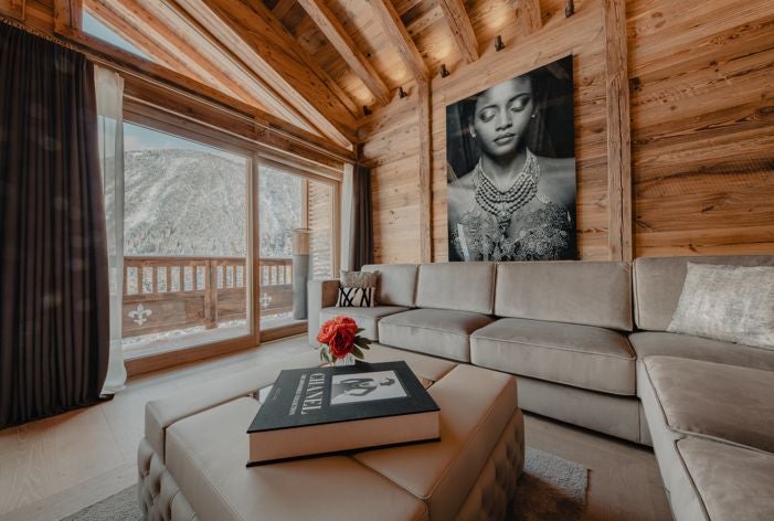 Luxurious alpine hotel room with modern design, featuring plush white bedding, panoramic mountain views, and elegant wooden accents in Courchevel, France.