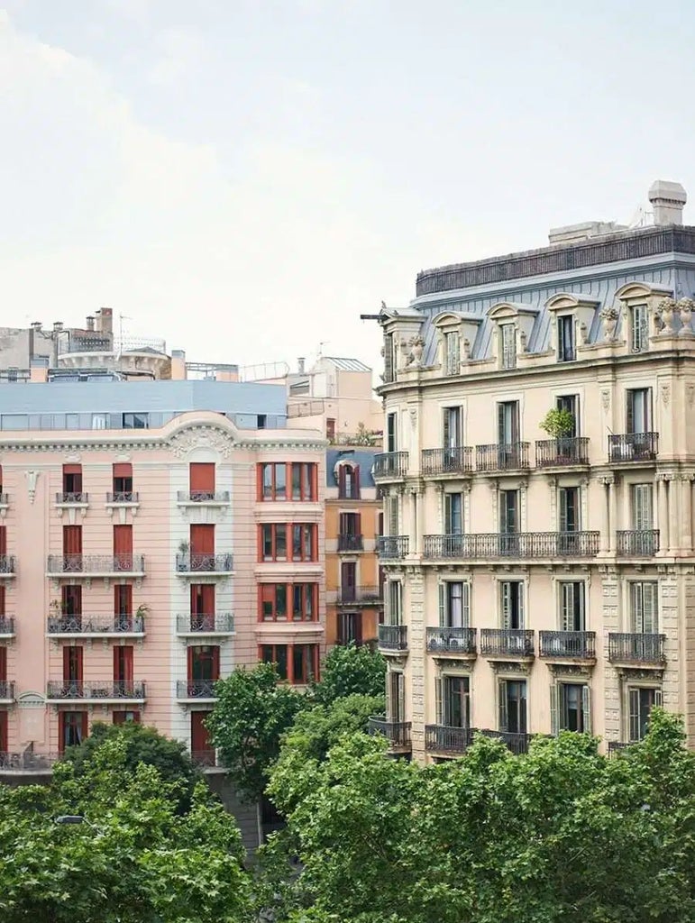 Elegant modern hotel room with minimalist white decor, large windows overlooking Barcelona's Gran Via, featuring clean lines and stylish contemporary furnishings