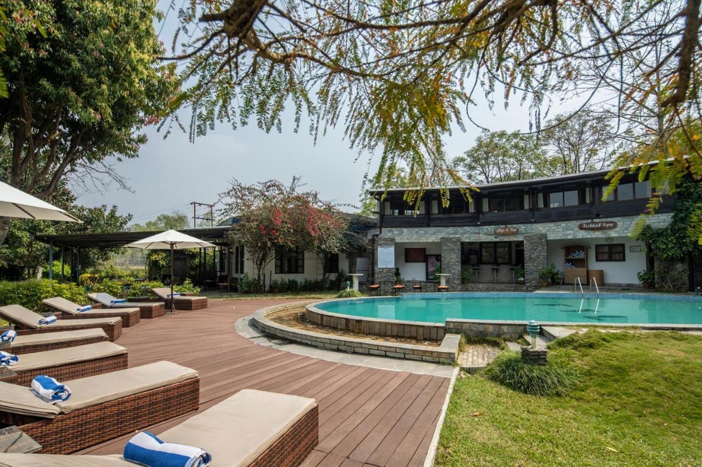 Stone-built luxury lodge with traditional Nepalese architecture nestled against mountains, featuring manicured gardens and panoramic Himalayan views