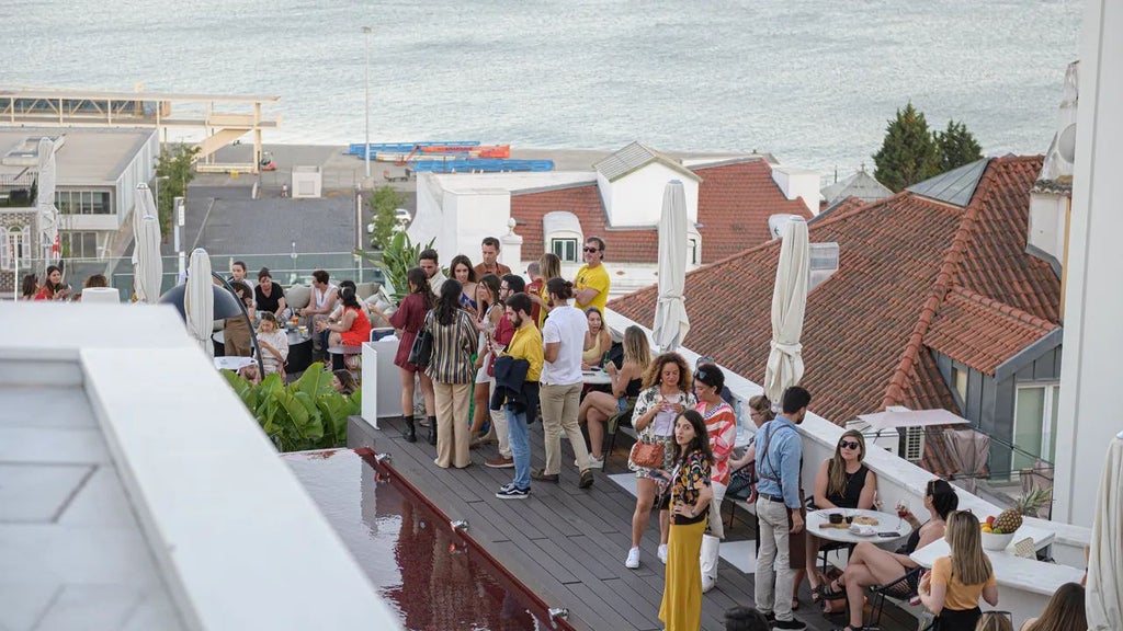 Elegant boutique hotel terrace overlooking Lisbon's historic Alfama district with vibrant red rooftops and traditional Portuguese architecture at sunset