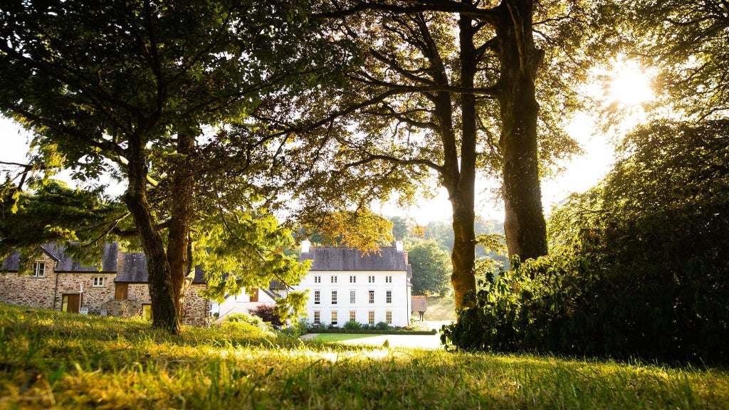 Luxurious countryside manor nestled in lush Pembrokeshire landscape, featuring elegant stone facade, manicured gardens, and serene woodland setting