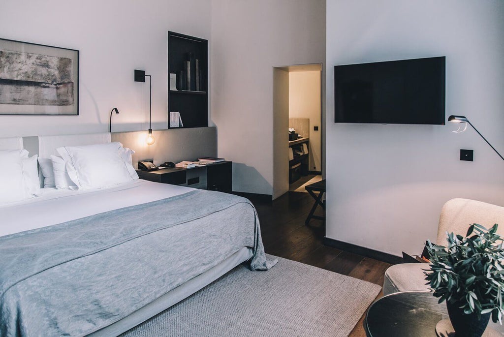 Elegant boutique hotel room with contemporary Spanish design, white walls, wooden floors, and minimalist luxury furnishings in neutral tones