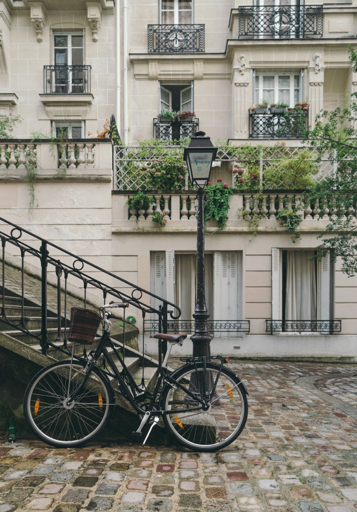 Charming cobblestone street in Montmartre, Paris, with elegant white Parisian buildings, historic Sacré-Cœur Basilica in background, vibrant artist scene