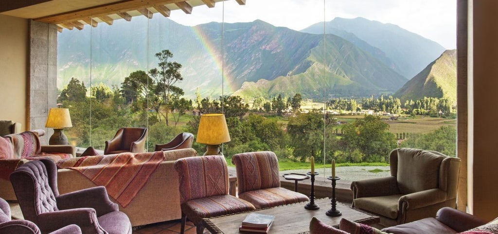 Luxurious mountain lodge with stone facades nestled in Sacred Valley, surrounded by Andean peaks and manicured gardens at sunset