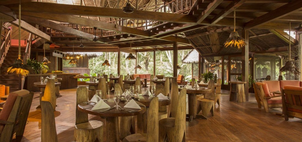 Luxury eco-lodge in Amazon rainforest with thatched-roof cabanas connected by wooden walkways, surrounded by lush jungle canopy