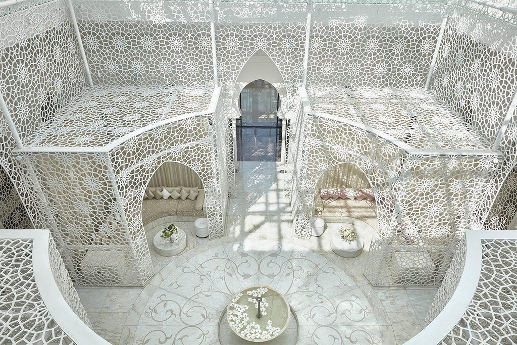 Elegant Moroccan hotel exterior featuring ornate Islamic architecture, white facade, grand entrance with archways and manicured gardens