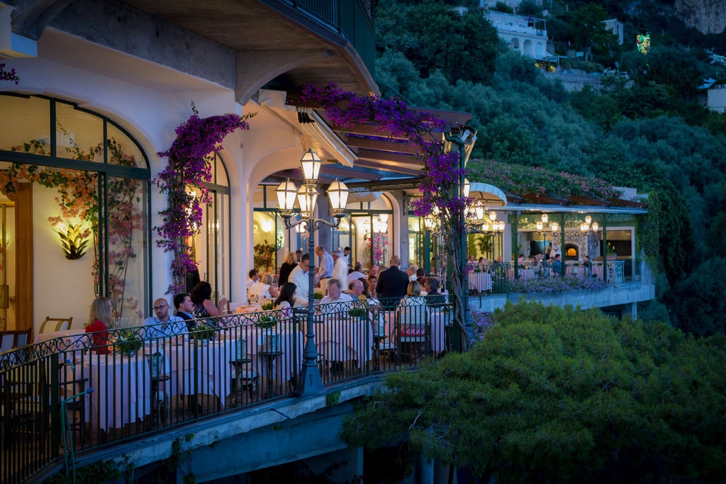 Luxurious cliffside hotel in Positano with private terraces overlooking the Amalfi Coast's turquoise Mediterranean waters at sunset