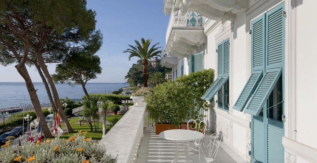 Historic beachfront Grand Hotel Miramare in Italy with elegant white facade, palm trees, and Mediterranean views from its seaside terrace