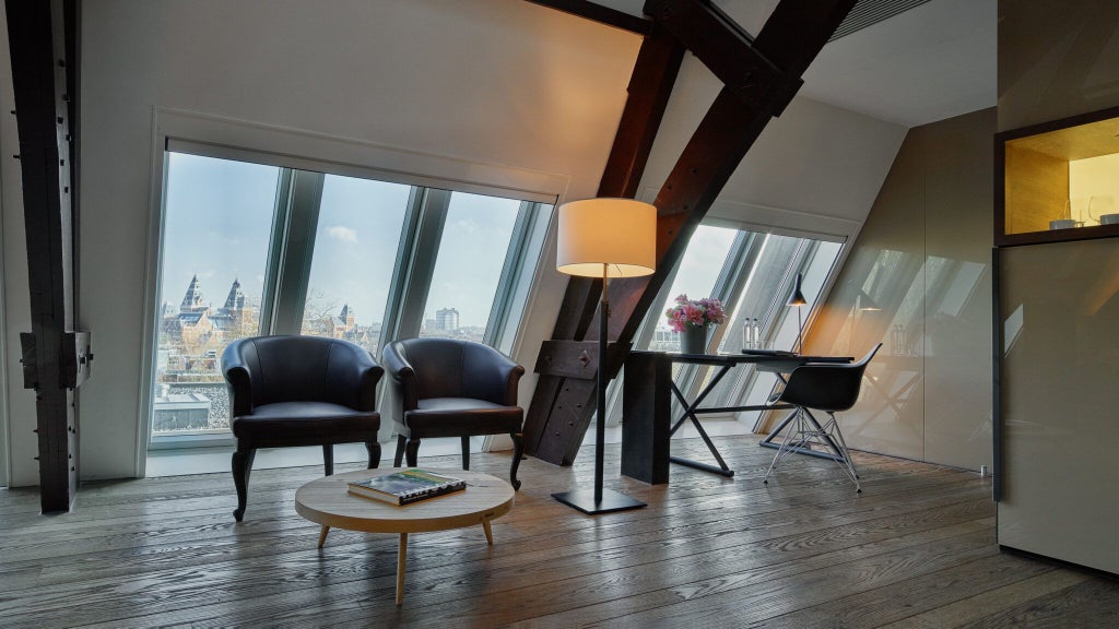 Elegant grand junior suite with modern design, featuring floor-to-ceiling windows, plush furnishings, and soft neutral tones at Conservatorium Hotel in Netherlands