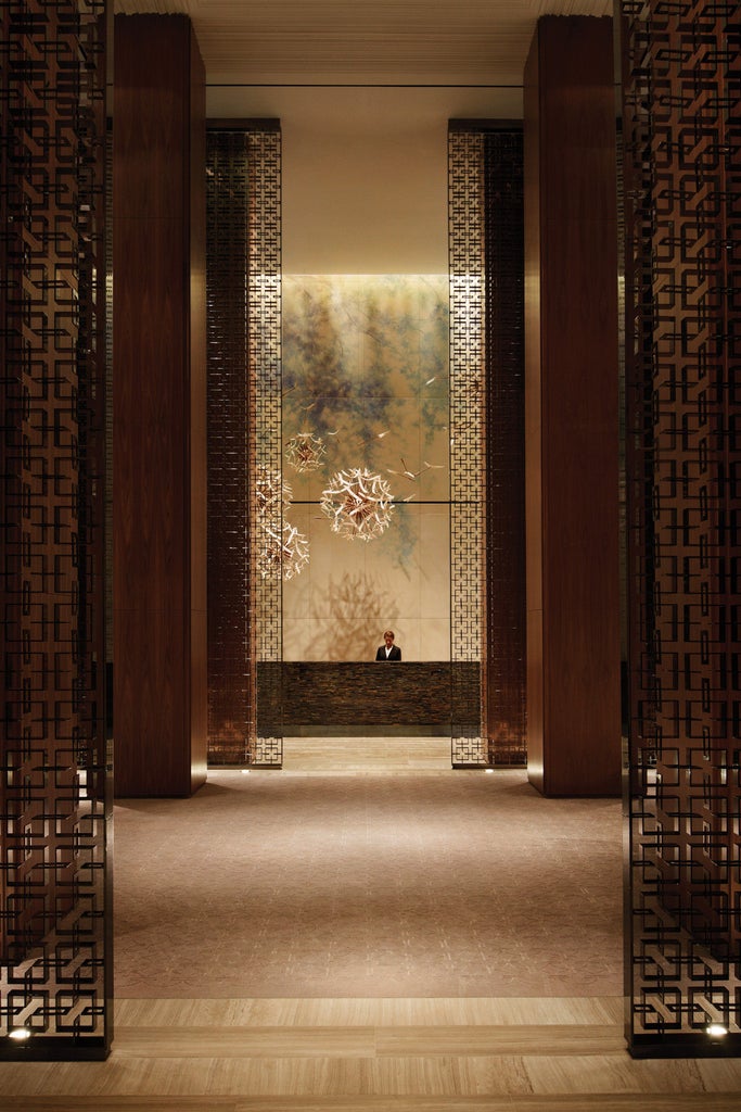 Modern glass skyscraper of Four Seasons Toronto rising above Yorkville, with elegant entrance portico and manicured landscaping