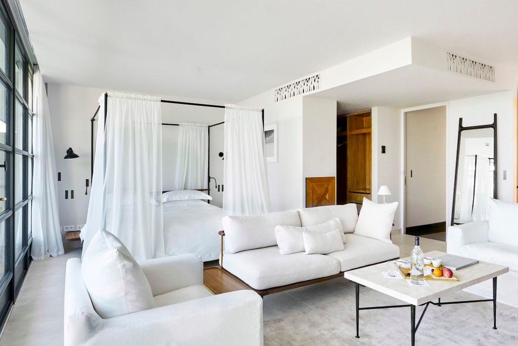 Luxurious hotel suite with floor-to-ceiling windows, contemporary furnishings, freestanding bathtub, and panoramic views of Provence countryside