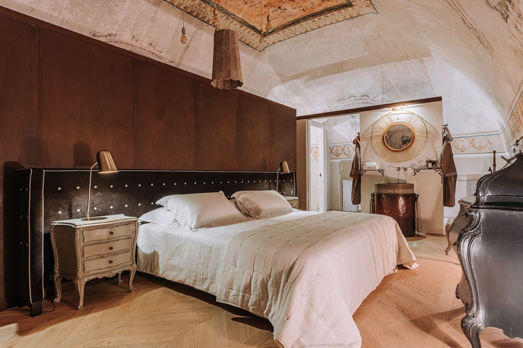 Elegant Italian luxury suite with ornate chandelier, plush king bed, marble floors, and expansive windows overlooking historic architecture in soft neutral tones