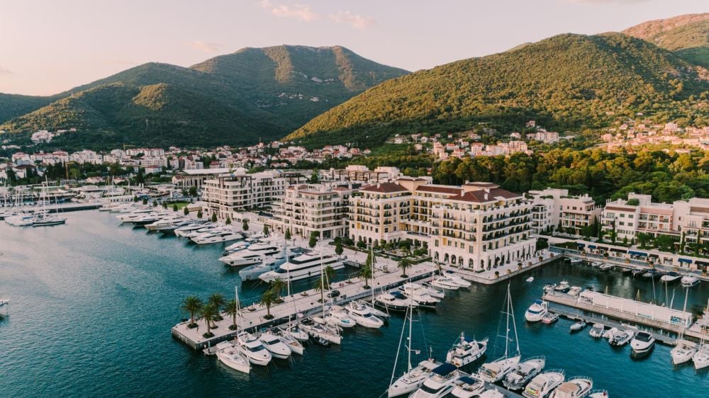 Opulent waterfront Regent hotel in Porto Montenegro with terracotta roof, venetian-style architecture, and private yacht marina at sunset