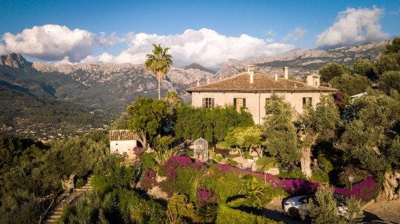 Elegant stone luxury retreat nestled in scenic Spanish landscape, with lush gardens, stone architecture, and panoramic mountain views at sunset