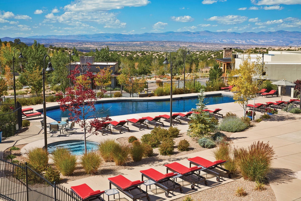 Elegant adobe-style luxury resort with terracotta walls nestled in Santa Fe's desert landscape, featuring native landscaping and mountain views