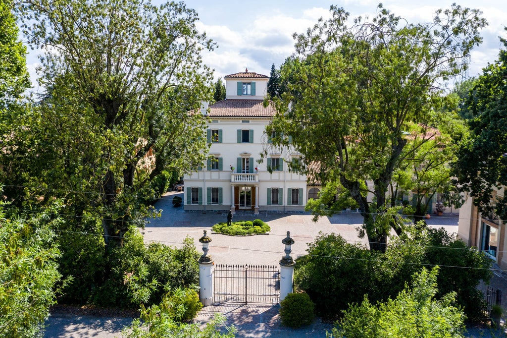 Elegant Italian countryside hotel with stone facade, manicured gardens, and historic architecture amidst rolling green Emilian hills