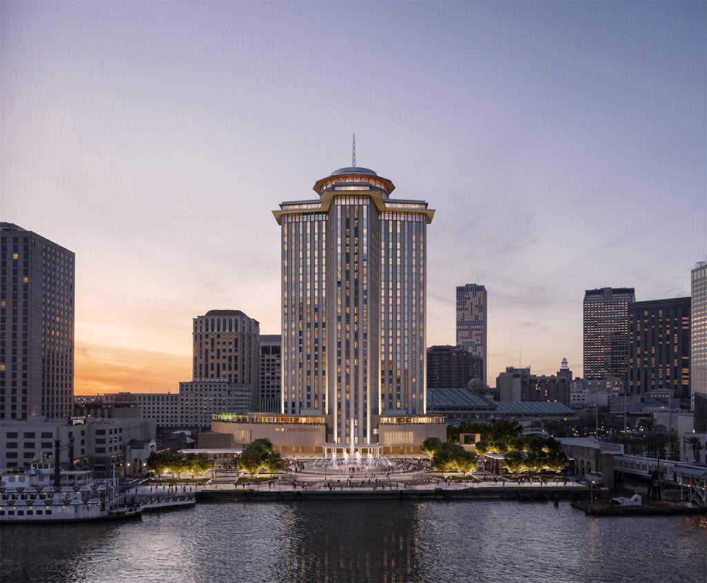 Elegant glass skyscraper of Four Seasons New Orleans with curved facade reflecting cityscape, set against vibrant sunset and palm trees