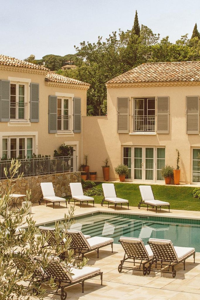 Elegant swimming pool surrounded by Mediterranean gardens at Lou Pinet hotel, featuring rustic stone walls and chic loungers at dusk