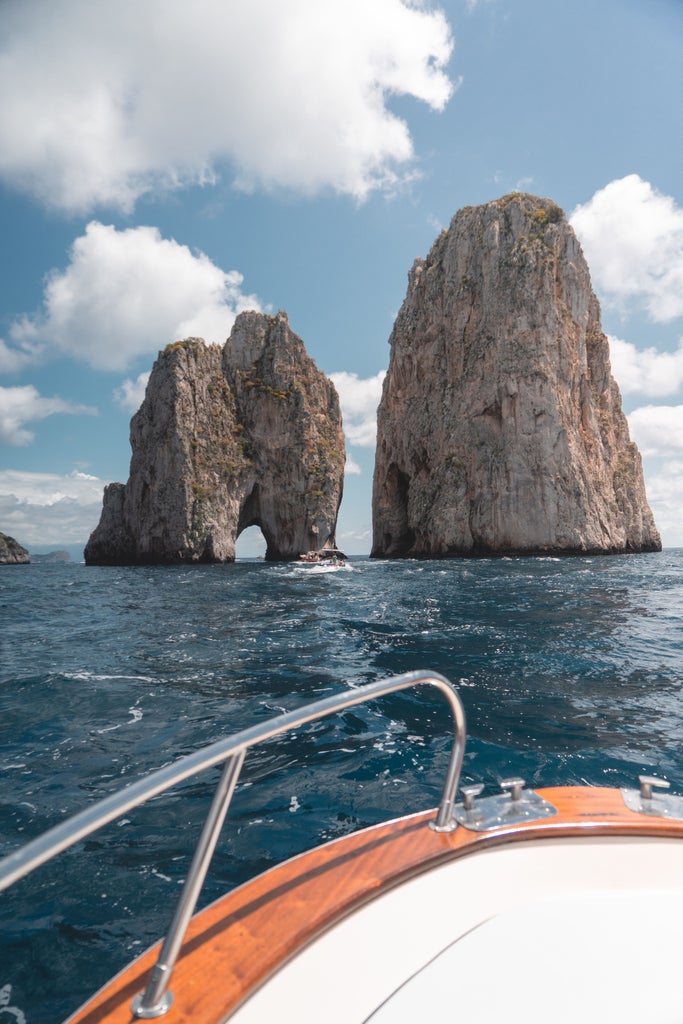 Luxury yacht anchored near Positano's colorful cliffside homes along Amalfi Coast, Mediterranean Sea glittering in sunlight