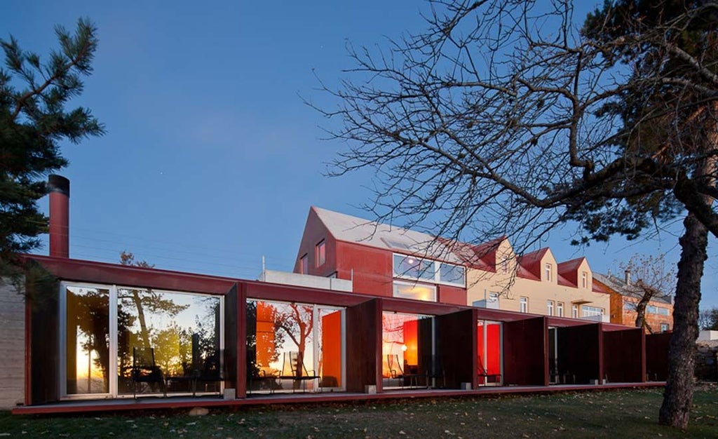 Mountain hotel with minimalist white design, nestled in lush Serra da Estrela landscape, featuring clean architecture and panoramic alpine views in Portugal's mountainous region.