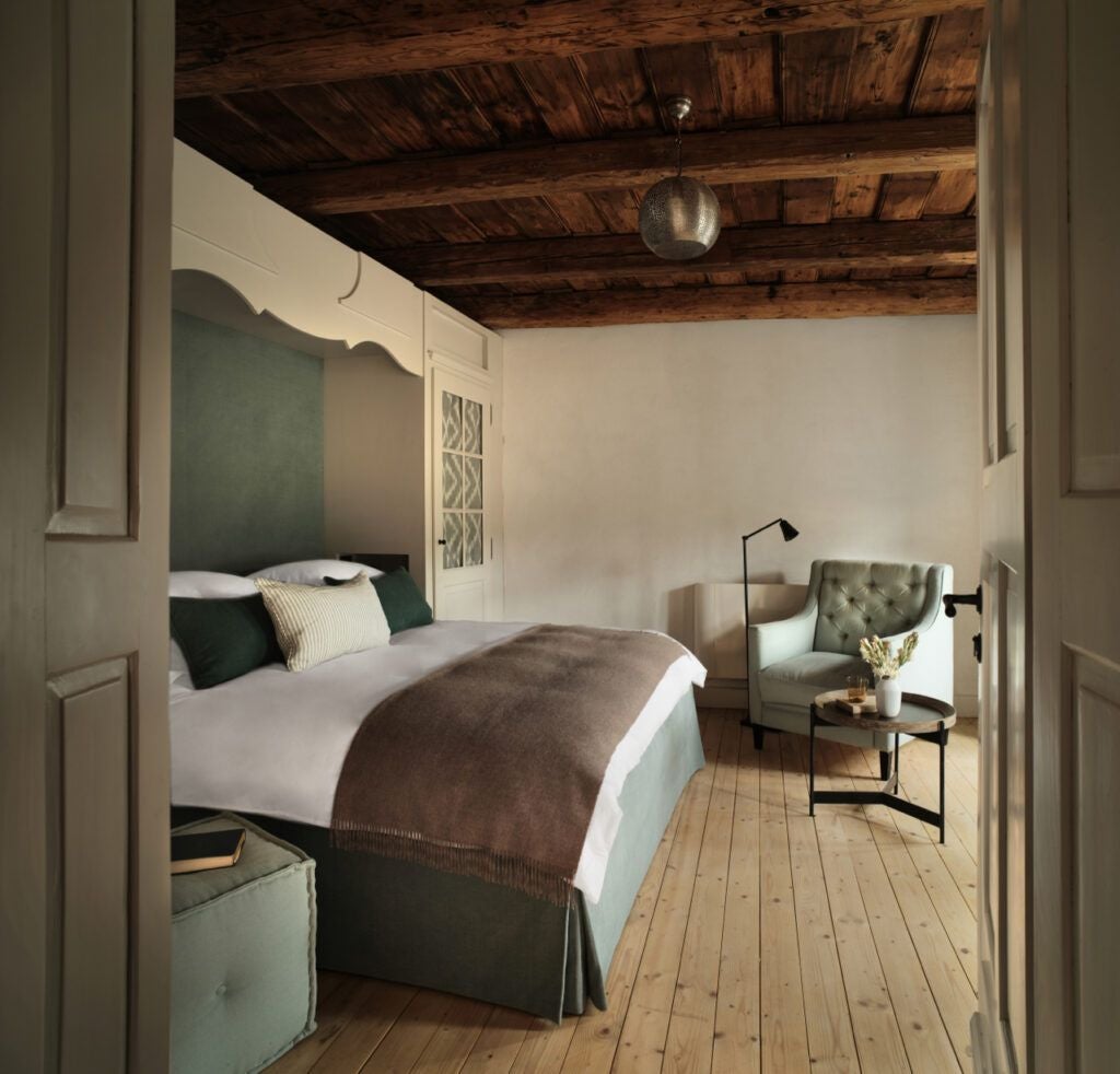 Elegant rustic bedroom in Transylvanian guesthouse, featuring wood-paneled walls, antique furnishings, and soft natural light highlighting traditional Romanian decor