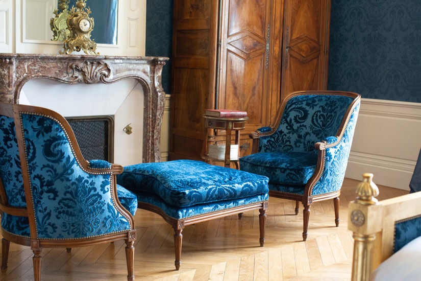 Elegant King bedroom with crystal chandelier, French doors, period furnishings, and panoramic countryside views at Château du Grand-Lucé