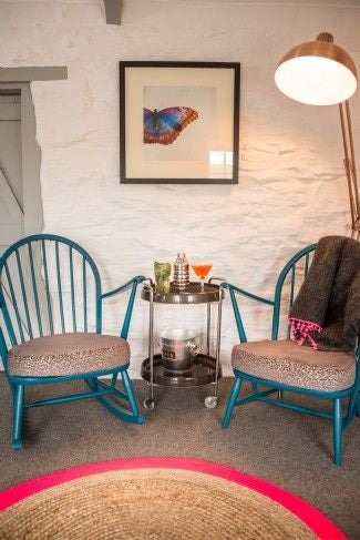 Elegant beachfront cottage with white-washed walls, thatched roof, and blooming garden pathway leading to a blue wooden door by the sea