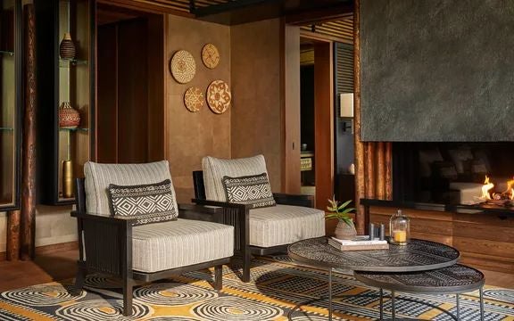 Luxurious Rwandan suite with floor-to-ceiling windows, elegant wooden furnishings, and a private terrace overlooking lush tropical forest landscape