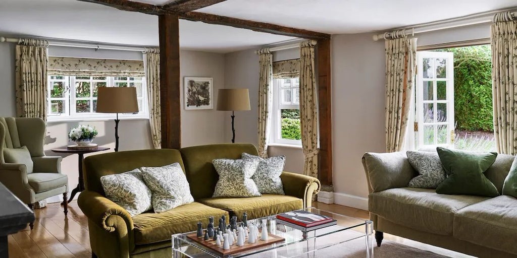 Elegant Dower House bedroom at Coworth Park, featuring plush cream furnishings, antique wooden furniture, and soft natural light through large windows