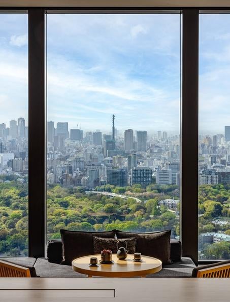 Minimalist Japanese luxury hotel lobby with soaring black stone walls, traditional washi paper screens, and elegant ikebana displays