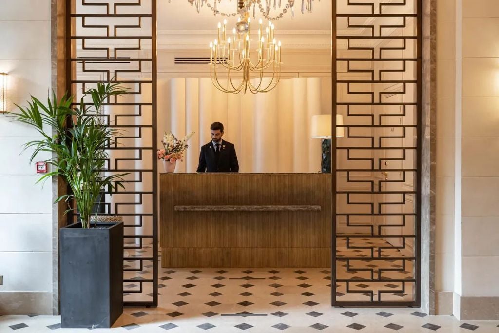 Elegant French Art Deco hotel facade with ornate stone carvings, wrought iron balconies, and classic Parisian windows in warm beige tones