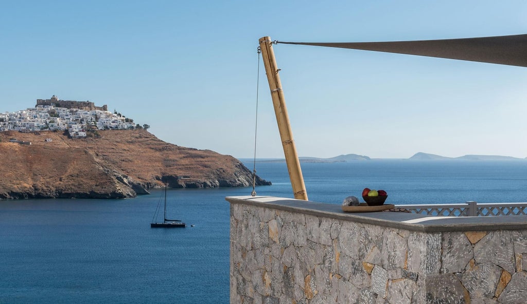 Luxury white-washed suites with blue accents overlooking the Aegean Sea, traditional Cycladic architecture framing a breathtaking Greek island sunset