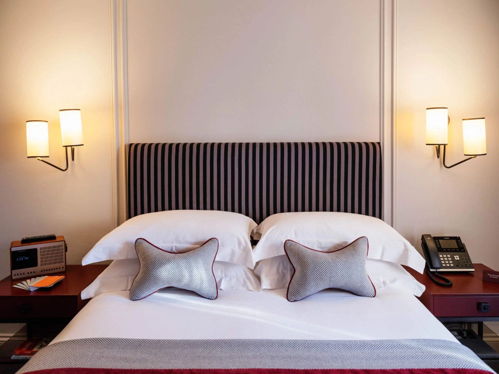 Classic, elegant hotel room with period furnishings, soft neutral color palette, and large windows offering natural light in a historic United Kingdom setting